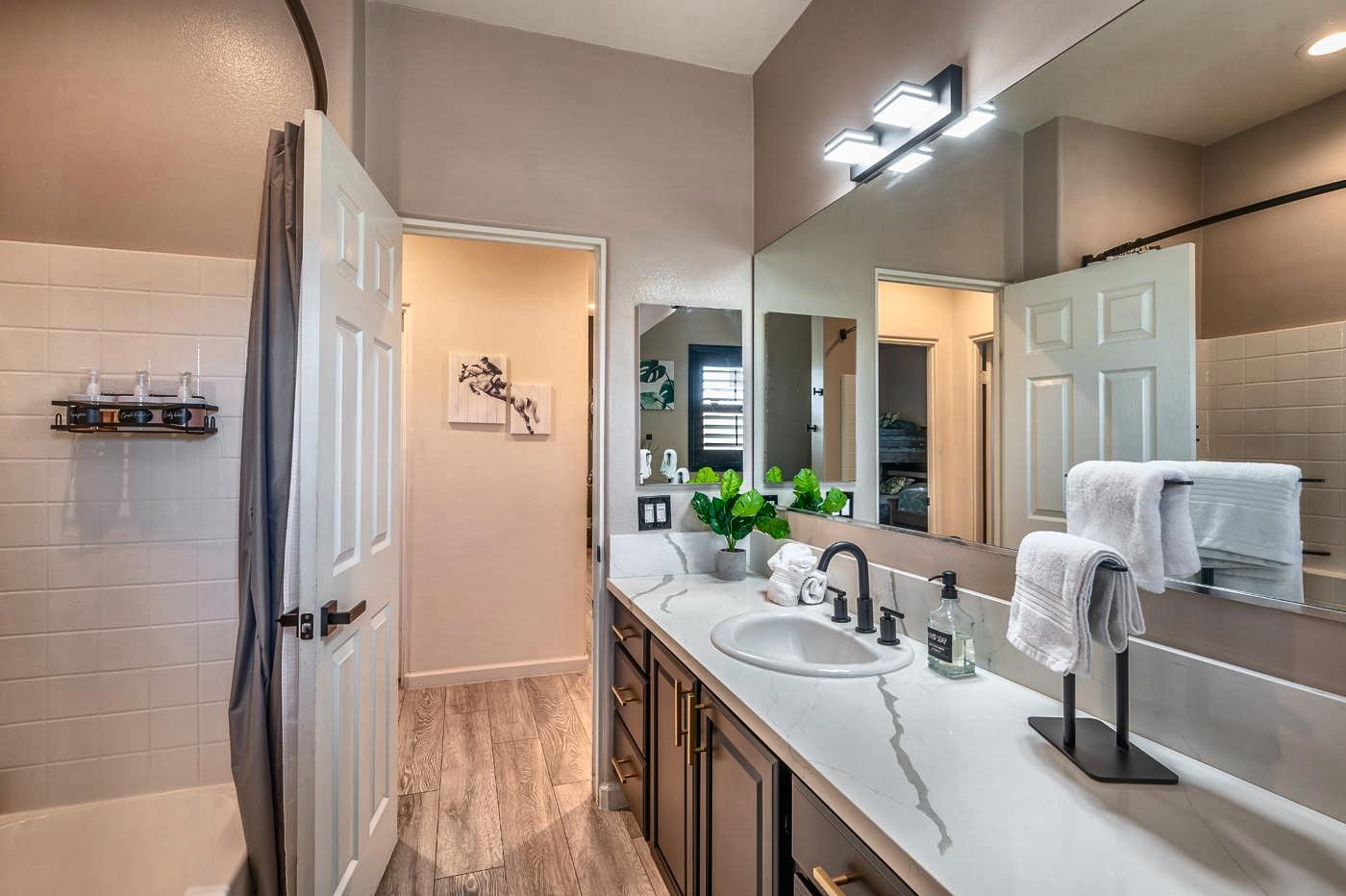 Hall bathroom with tub and show jumping artwork in the hallway