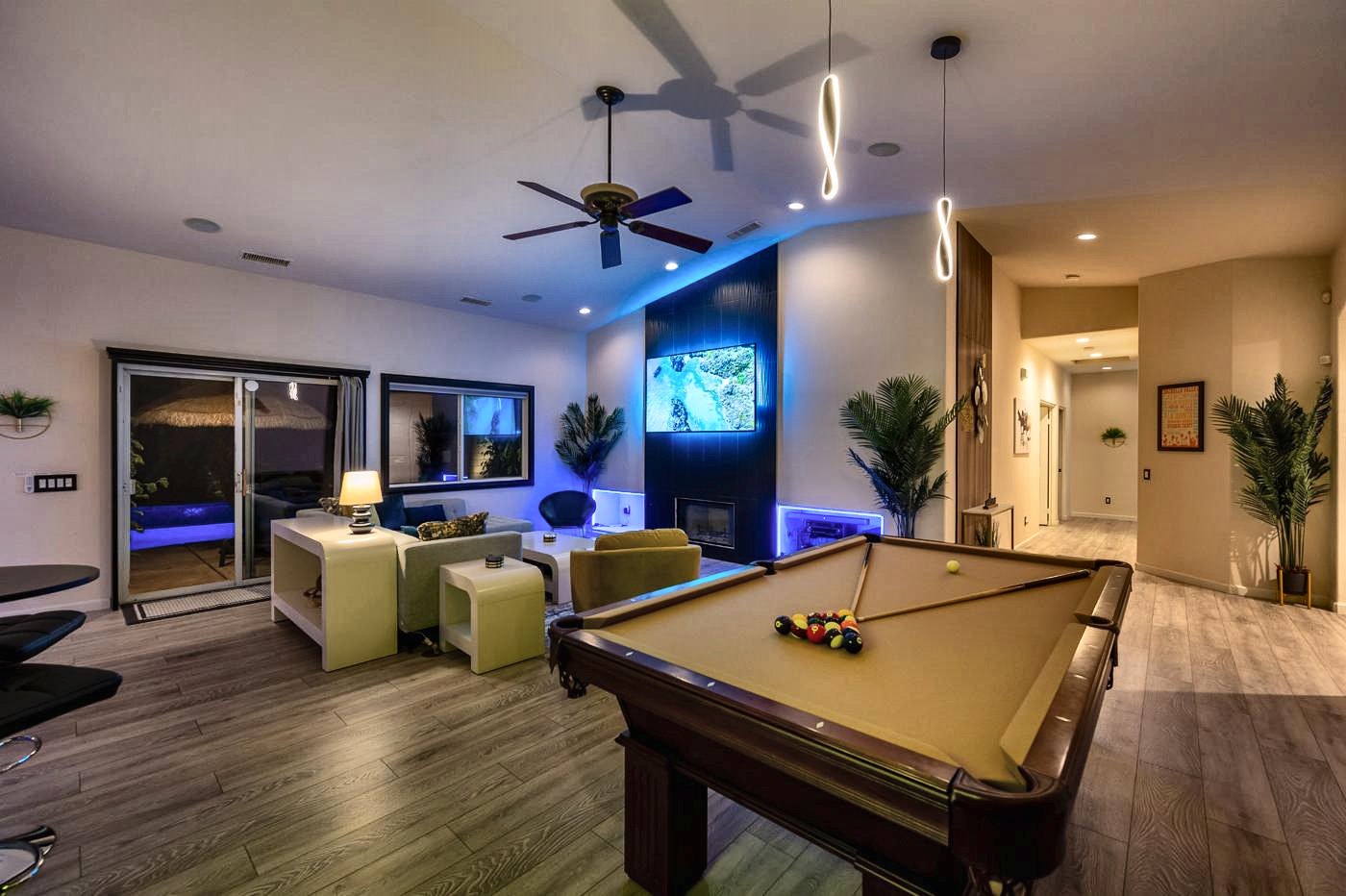 Pool table in the great room at night with the backlit TV wall and fireplace