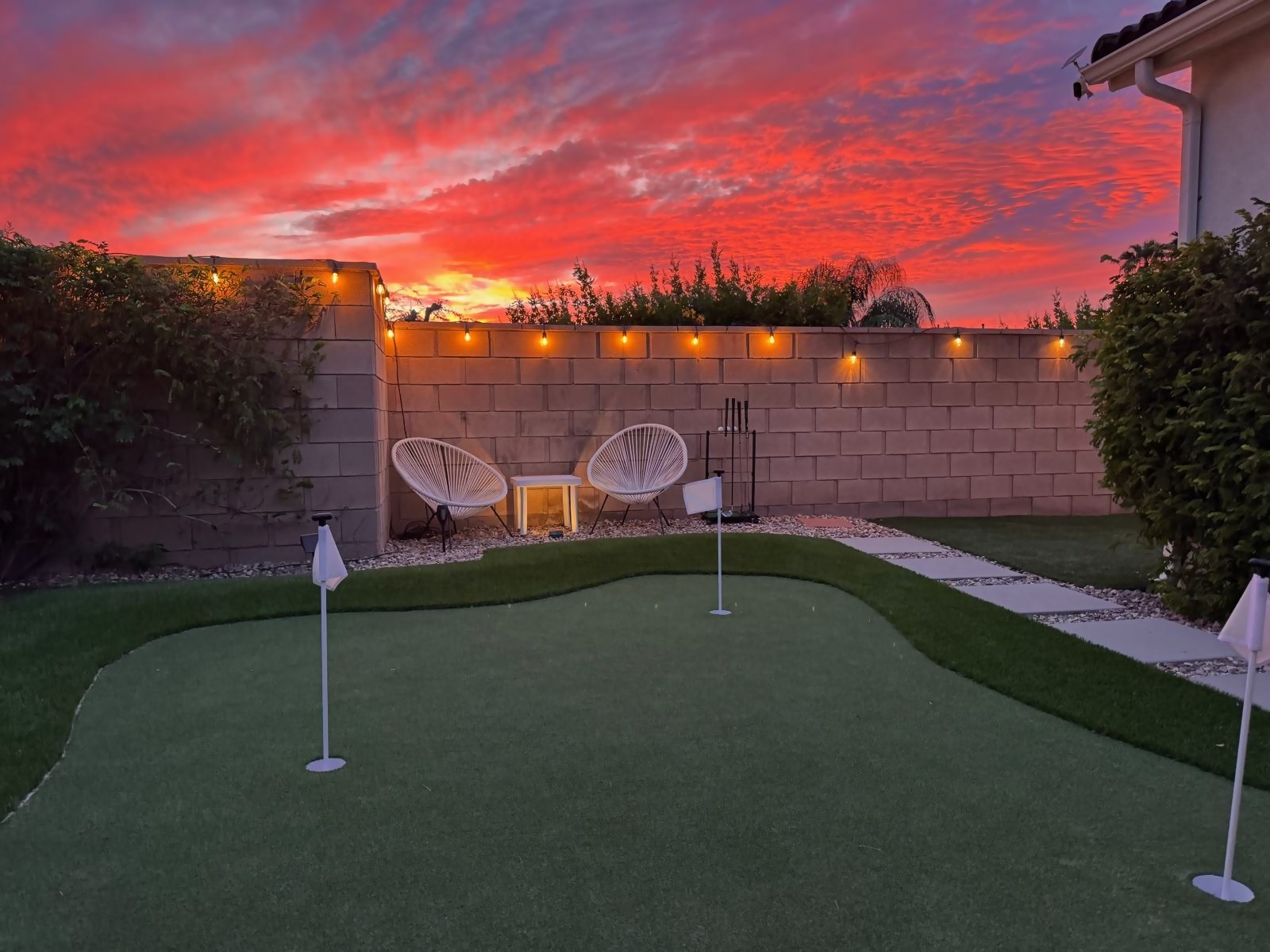 Putting green at sunset with glowing string lights along the wall
