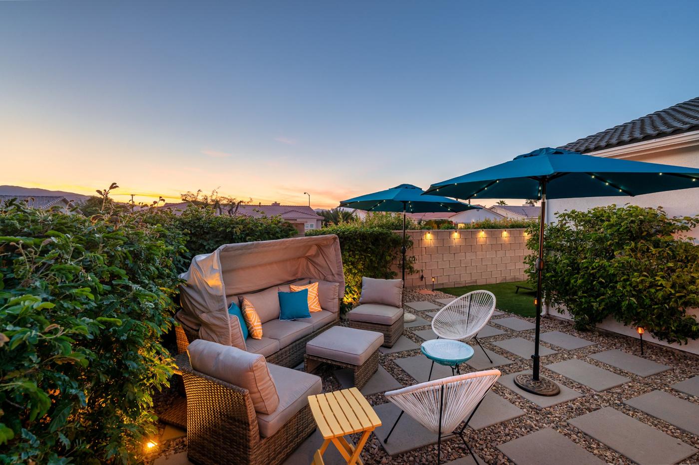 Lounge area with canopy daybed under umbrellas with string lights at dusk