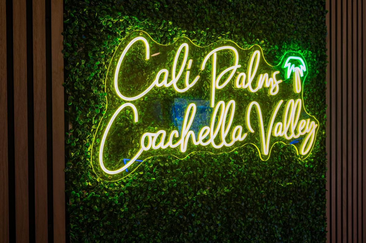 Cali Palms Coachella Valley neon sign on a green living wall